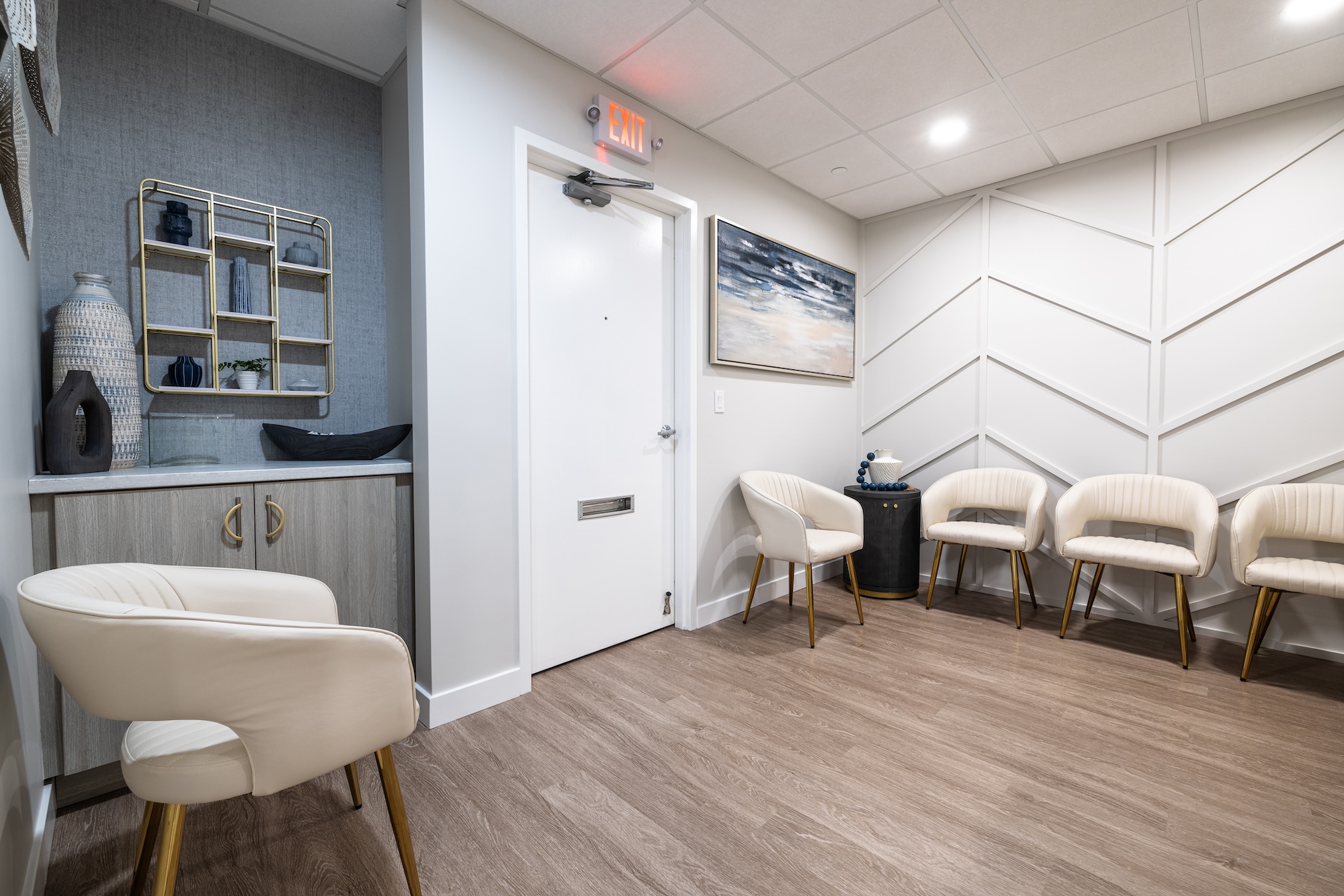 The image shows a modern waiting room with a clean and minimalist design, featuring a row of chairs, a reception desk, and a contemporary aesthetic.