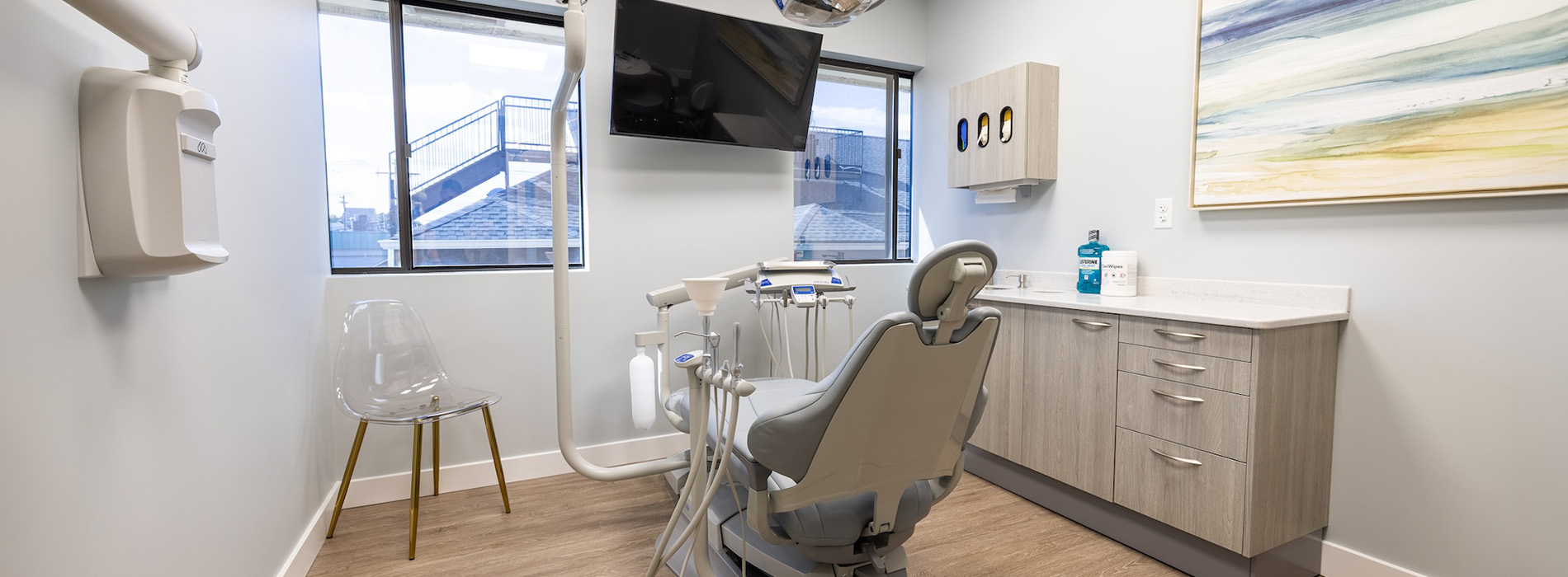 The image shows a modern dental clinic interior with various pieces of equipment, including a dental chair and an X-ray machine.