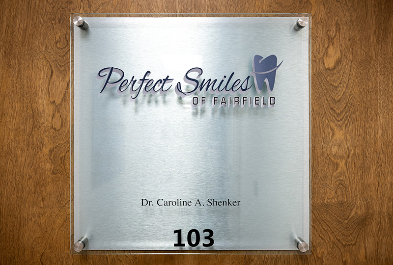 A professional dental office sign with the name  Perfect Smiles  and a logo, indicating a dental practice.