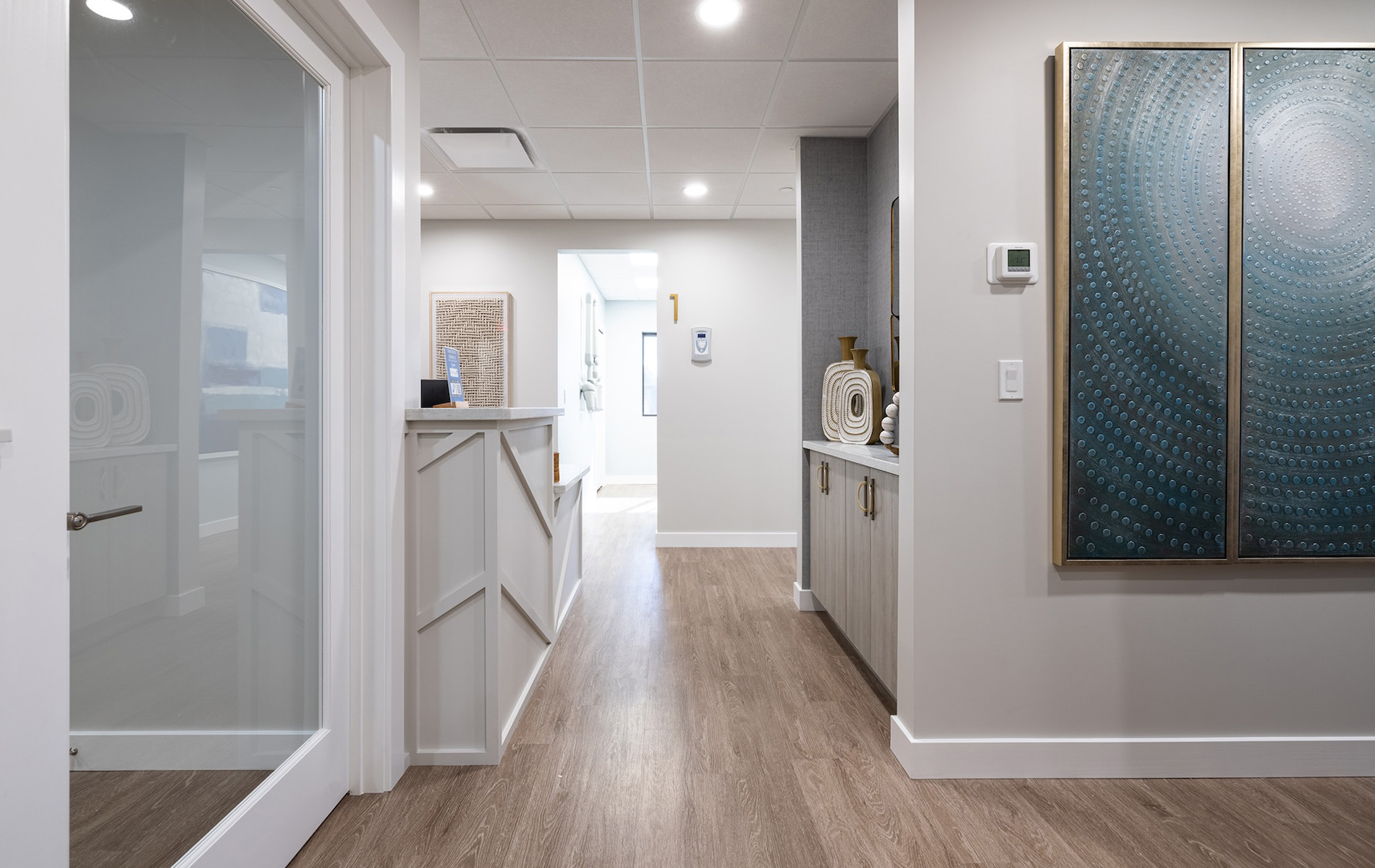 The image depicts a well-lit, modern interior hallway with hardwood flooring and contemporary furnishings.